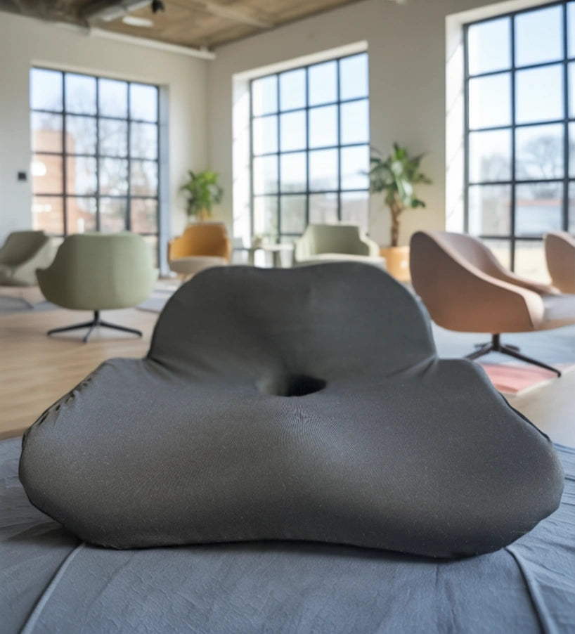 Black memory foam seat cushion (posture cushion) -Soothe- on a bed with a modern room in the background