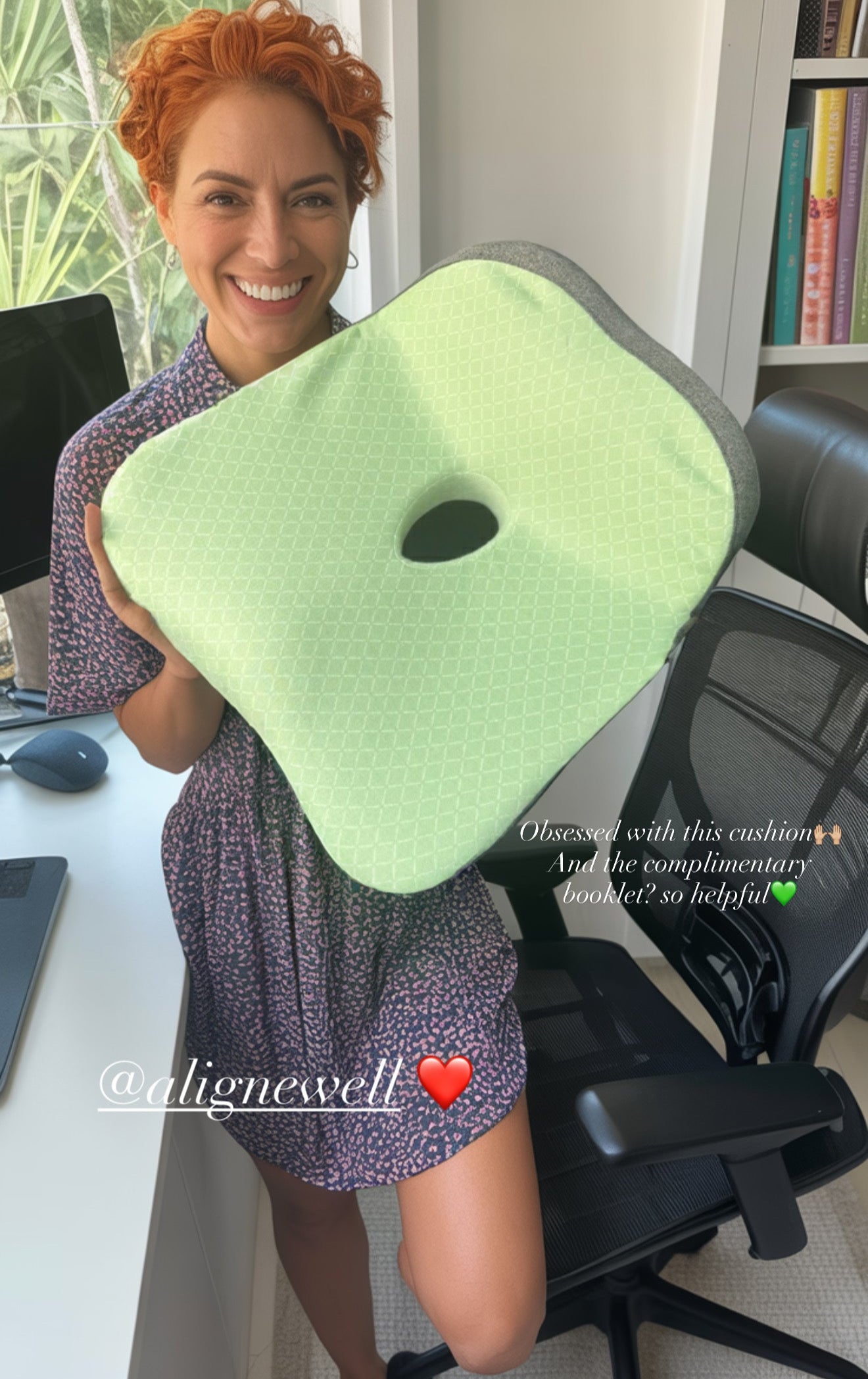 Person holding a green posture cushion in a home office setting