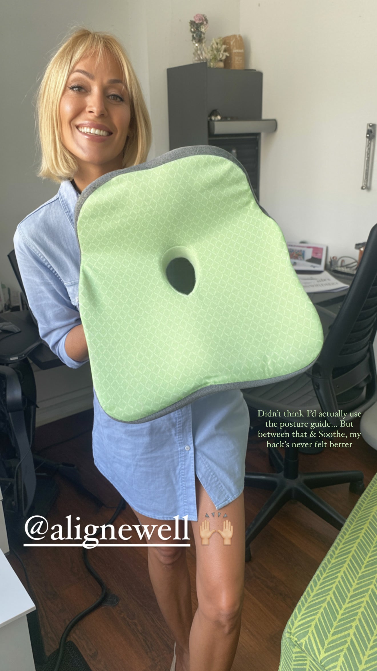 Person holding a green posture cushion with a hole, likely an office chair cushion, in an office setting.